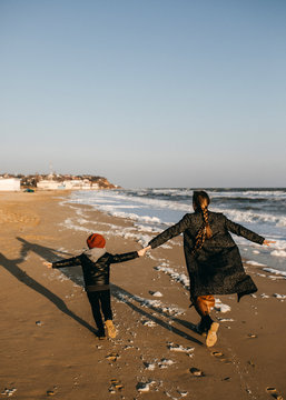 mother and child, running on the beach from waves.