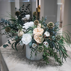 Wedding bouquet of white roses, lisianthus, peonies and eucalyptus branches in a white vase in store window