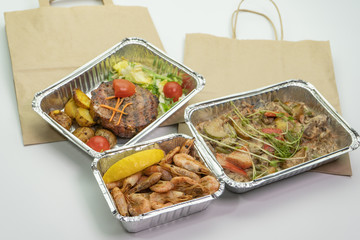 Paper bag meat and steak in their foil containers on an isolated white background. The view from the top,