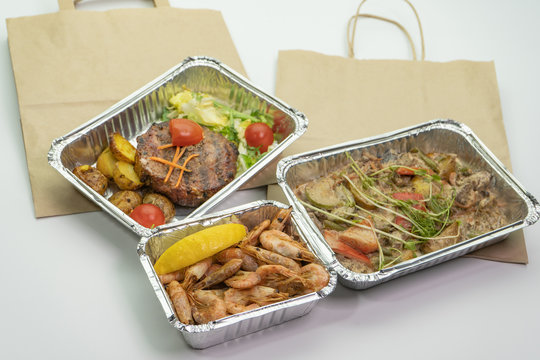 Paper bag meat and steak in their foil containers on an isolated white background. The view from the top,