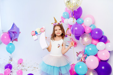 Obraz na płótnie Canvas Unicorn Girl holding gold confetti air baloon and letter 7. Idea for decorating unicorn style birthday party. Unicorn decoration for festival party girl.