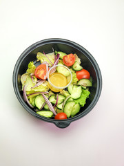 Plastic plate with vegetable salad on an isolated white background. The concept of food delivery.