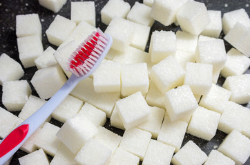 toothbrush on the background of the sugar cubes of refined sugar, preventing tooth decay, caring for the health of your teeth, the causes of caries