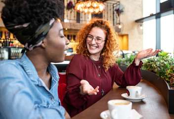 Two women talking to eachother at a cafe.