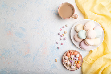 Colored zephyr or marshmallow with cup of coffee and dragees on white concrete background. top view, copy space.