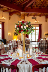 Dining setting for a wedding ceremony in red and white colors with bouquet of roses