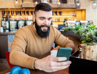 Caucasian man looking at his phone in the cafe.