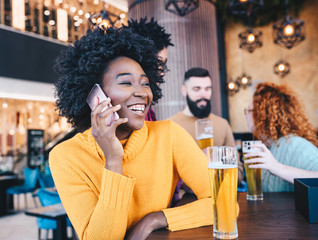 Woman talking on the phone while her friends are talking in the cafe.