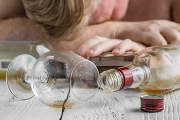 Alcohol addicted man at the table. Sad depressed male adult having troubles with alcohol.
