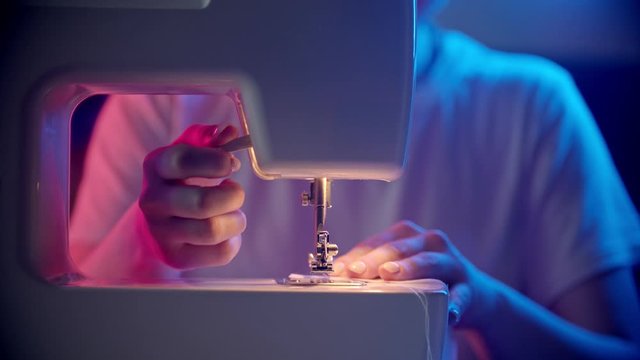 Young woman seamstress sewing a light white cloth