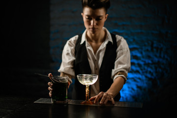 bartender's hands on glass and mixing cup with green cold cocktail stand on bar counter