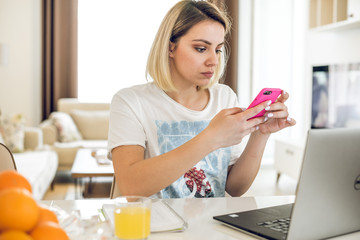 Young woman working from home at kitchen table.