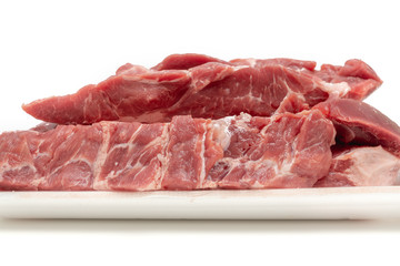 Raw pork meat cuts in white container close up isolated on white background. Fresh slices without bone