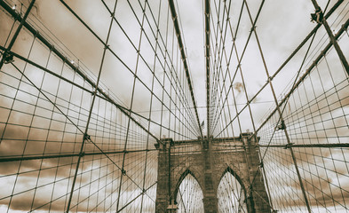 Fototapeta premium The Brooklyn Bridge at sunset, major pylon and cables against cloudy sky