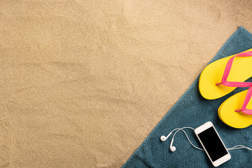 Summer vacation composition. Flip flops, and smartphone on sand background. Travel vacation concept. Summer background. Border composition made of towel