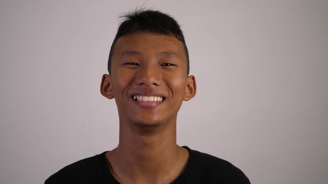 The asian boy smiles and looks happy with white background