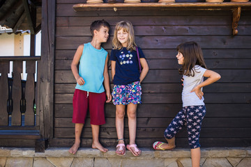 Boy whispering something to one girl, other girl eavesdropping.