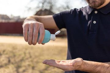 Hand sanitizer alcohol gel rub clean hands hygiene prevention of coronavirus virus outbreak. Man using small portable bottle of antibacterial sanitiser. Antiseptic drops into hand. Drops in the air