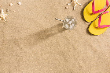 Fototapeta na wymiar Summer fashion, summer outfit on sand background. Yellow flip flops and seashells. Flat lay, top view. Harsh light with shadows