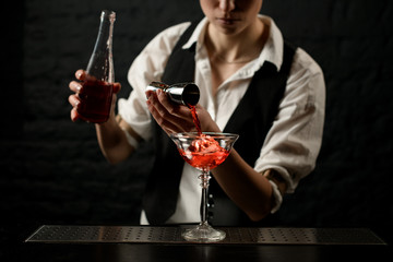 professional bartender masterly pours drink into glass on bar counter.