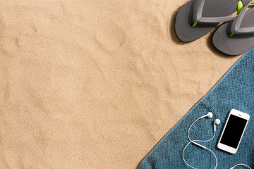 Top view flip flops and smartphone with copy space. Traveler accessories on sand. Travel vacation concept. Harsh light with shadows. Border composition made of towel