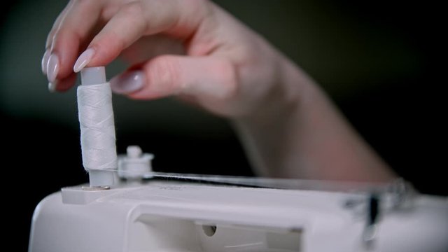 Hand of seamstress scrolls a skein of thread