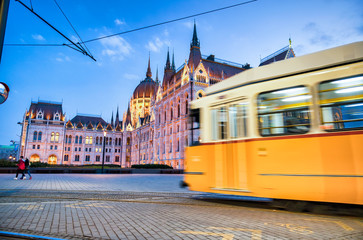 Fototapeta na wymiar Old yellow tram speeds up along city streets at night. The historical center of the capital of Hungary