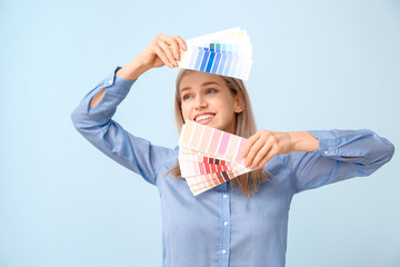 Young woman with paint palette on color background