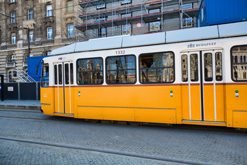 Plakat BUDAPEST, HUNGARY - MARCH 30, 2019: Old yellow tram speeds up along city streets. The historical center of the capital of Hungary