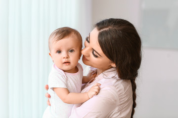 Happy mother with cute little baby near window