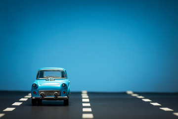 Blue toy car on an asphalt road.