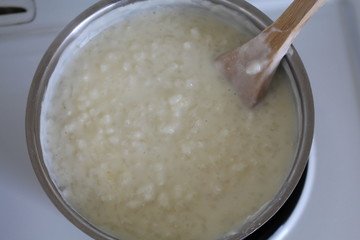 Cooking of rice porridge on oven, the first stage of preparation of national Finnish dish from rye flour and rice - Karelian pies