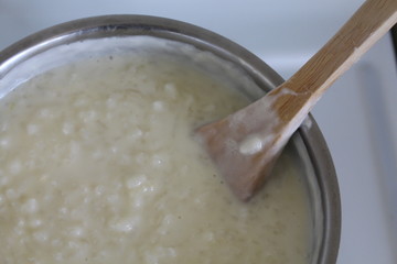 Cooking of rice porridge on oven, the first stage of preparation of national Finnish dish from rye flour and rice - Karelian pies