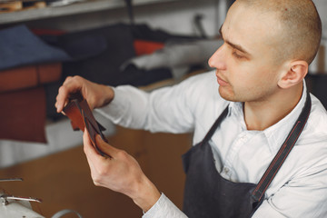 Man working with leather. Professional makes a wallet.