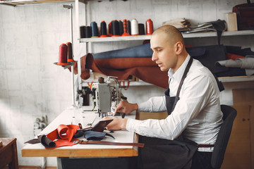 Man working with leather. Professional makes a wallet. Man uses a sewing mashine.
