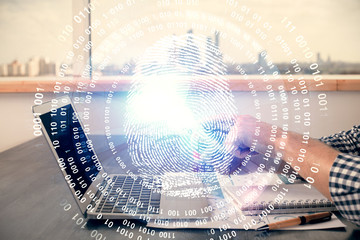 Double exposure of man's hands holding and using a digital device and fingerprint hologram drawing. Security concept.