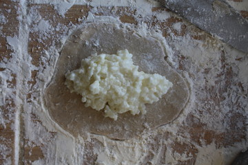 Stage of preparation of Karelian pies -Pirakka. Pies are located on a wooden board, being filled ready for baking. Dish of national cuisine - piirakka. Close-up.