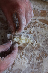 Stage of preparation of Karelian pies -Pirakka. Pies are located on a wooden board, being filled ready for baking. Dish of national cuisine - piirakka. Close-up.