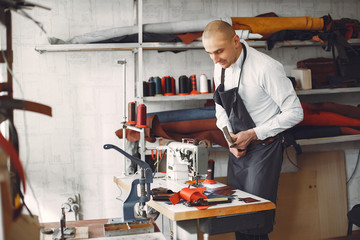 Man working with leather. Professional makes a wallet. Man uses a sewing mashine.