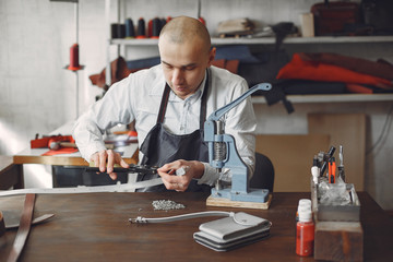 Man working with leather. Professional makes a holes. Man use device for holes.