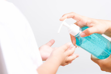Mother applying pump dispenser alcohol gel cleaning washing hands little child