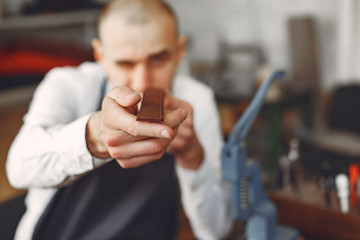 Obraz premium Man working with leather. Professional makes a belts.