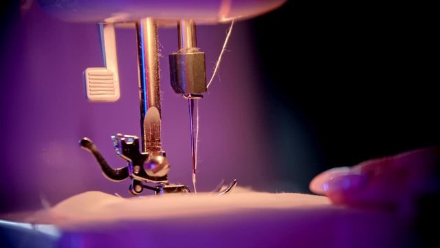 Hand of seamstress puts a cloth under the needle - sewing process