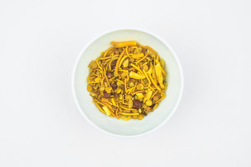Lot of spicy bombay mix stacked in a plain white colored plastic cup on a white background