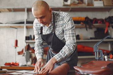 Man working with leather. Professional makes a wallet. erson measures the fabric.