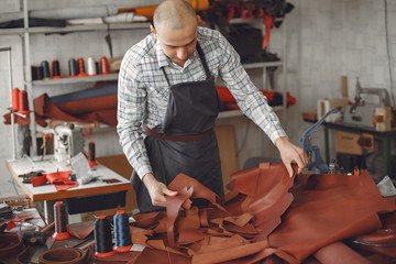 Man working with leather. Professional makes a wallet. erson measures the fabric.