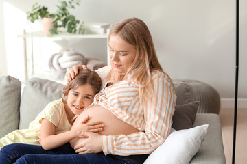 Beautiful pregnant woman with her little daughter at home