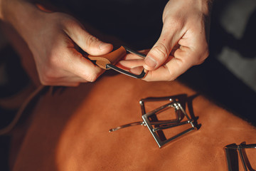 Man working with leather. Professional makes a belts.