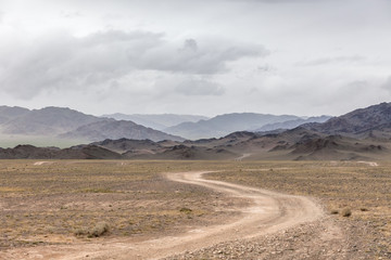 Winding dirt road through lush rolling hills of Central Mongolian steppe. Mongolian Altai