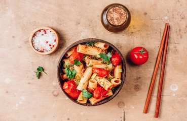 Pasta Tortiglioni with minced meat, tomato sauce and tomatoes in coconut bowl on rustic beige background